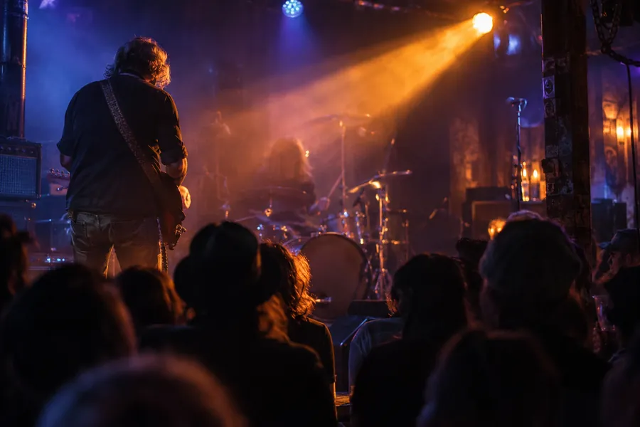Illustrative rock guitarist on a small stage under amber and blue lights